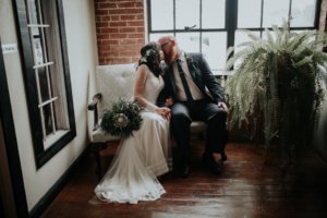 Bride and groom sitting on love seat kissing