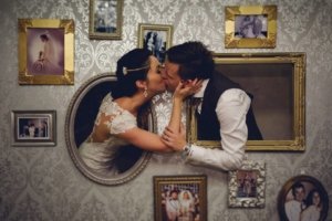 Bride and groom kissing through photo frames
